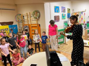 Ženska osoba pokazuje mališanima kako svira violinu