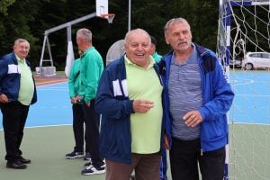 Dvojica muškaraca na sportskim susretima umirovljenika zagrljeni poziraju za fotografiju